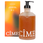 glazen fles met handpompje en oranjekleurige hand en body wash van cime